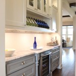 Burrows Cabinets' butler's pantry with Terrazzo door style in custom white and grey paint with half round posts, wine storage, glass panel doors, sweep blocks