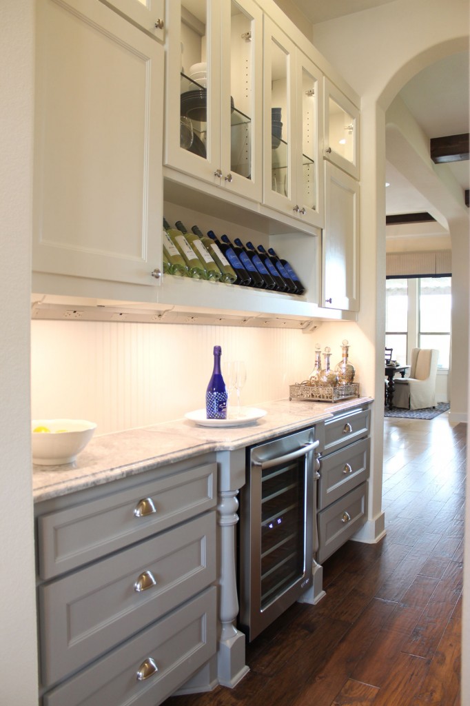 Burrows Cabinets' butler's pantry with Terrazzo door style in custom white and grey paint with half round posts, wine storage, glass panel doors, sweep blocks