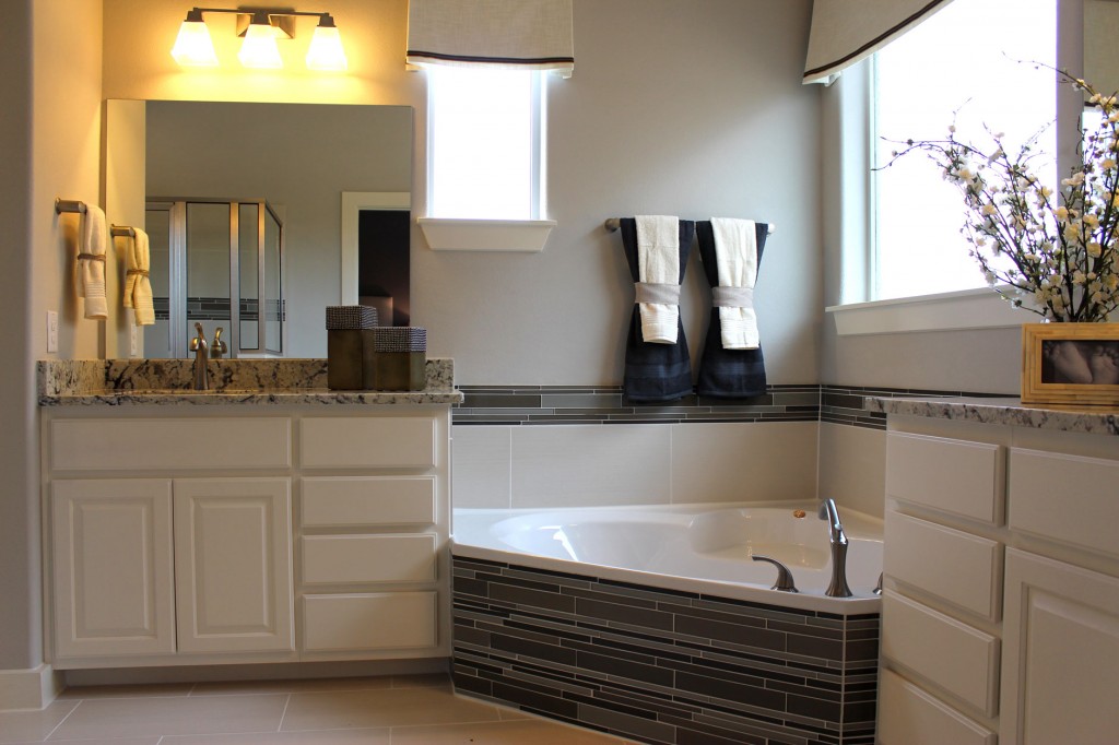 White primary bath cabinets by Burrows Cabinets with corner tub