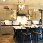 Burrows Cabinets kitchen with black island and gray wall cabinets, wood vent hood and modern crown