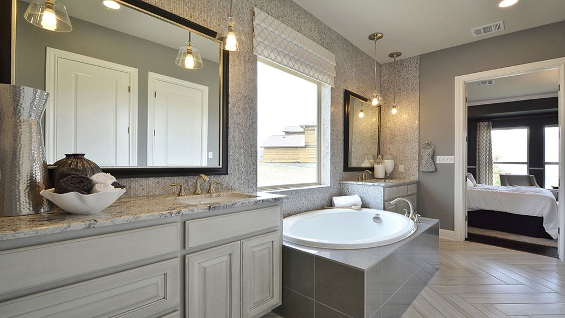 Burrows Cabinets master bath in bone with black glaze and double vanities divided by soaking tub