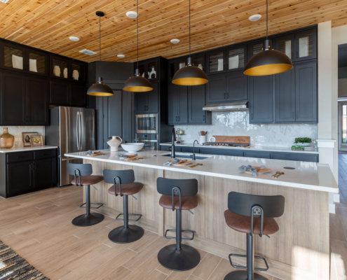 Kitchen with Breu soft black paint perimeter cabinets with glass uppers and Reveur woodgrain island cabinets