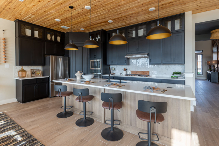 Kitchen with Breu soft black paint perimeter cabinets with glass uppers and Reveur woodgrain island cabinets