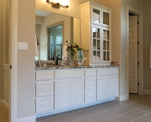 Burrows Cabinets' primary bath vanity with glass upper cabinet doors with mullions in bone