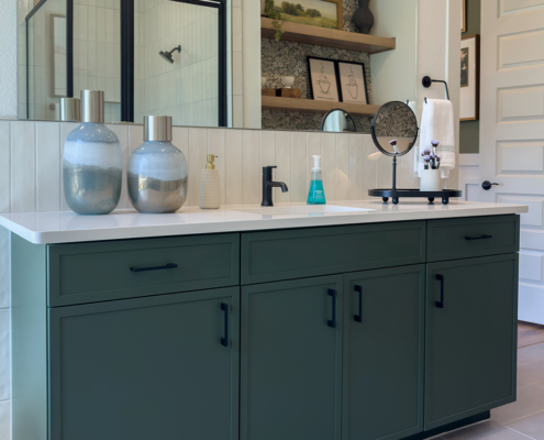 Bathroom vanity cabinets in Saba green with Slim Shaker doors and drawer fronts and black pull handles