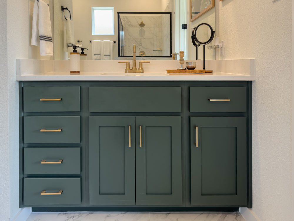 Bathroom vanity cabinets in Saba green with shaker doors and gold pulls