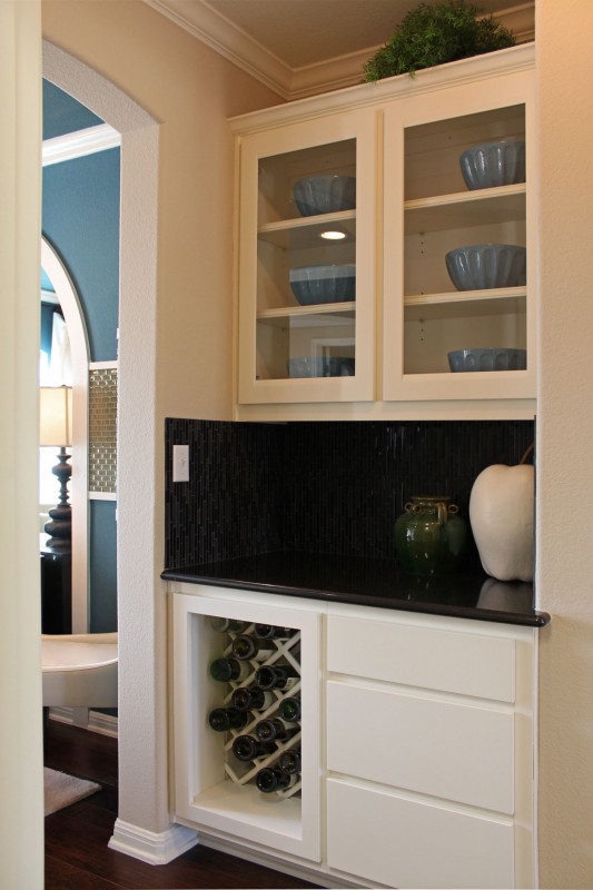 Burrows Cabinets' butlers' pantry with white cabinets in Briscoe design in Bone, glass panel doors and lattice wine rack