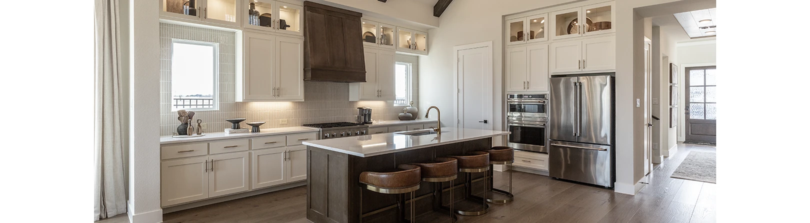 Kitchen cabinets in warm white perimeter, stained vent hood and stained wood island with wood beams