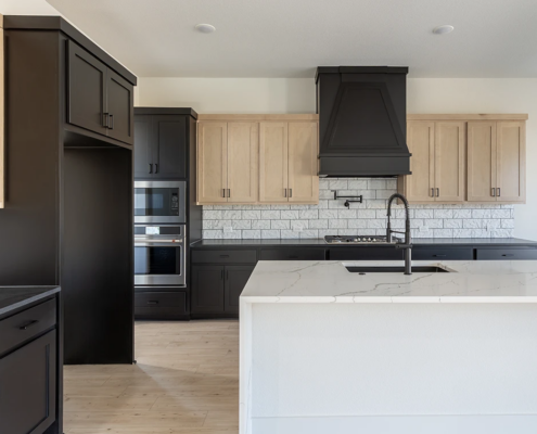 Kitchen with Maple Savaii upper cabinets and Breu base, oven and refrigerator cabinets and custom vent hood