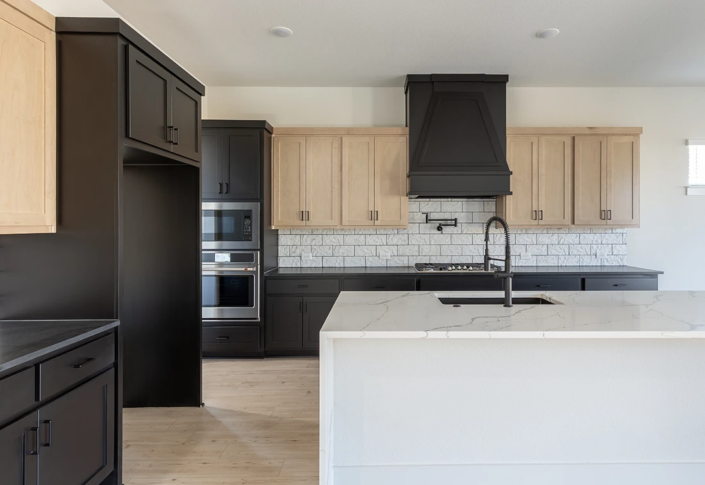 Kitchen with Maple Savaii upper cabinets and Breu base, oven and refrigerator cabinets and custom vent hood