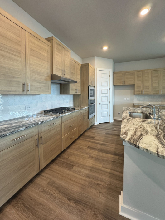 Kitchen cabinets in Laurent EVRGRN with 3 piece doors and EVRGRN vent hood