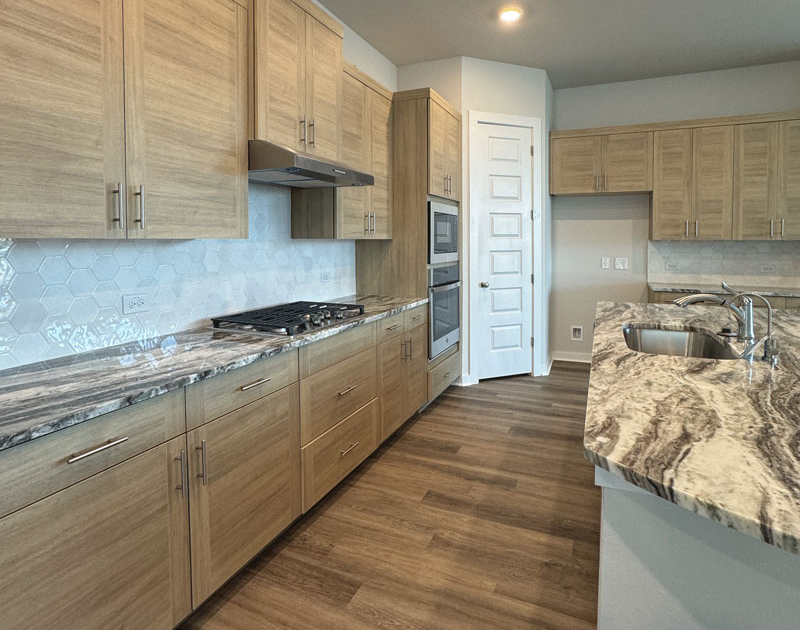 Kitchen cabinets in Laurent EVRGRN with 3 piece doors and EVRGRN vent hood