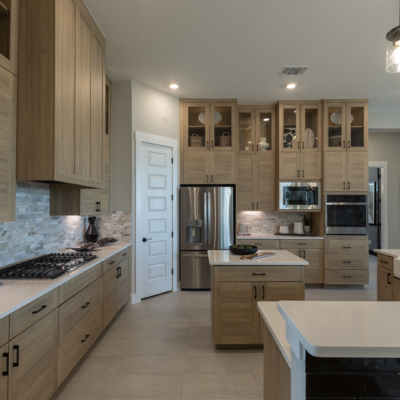 Kitchen cabinets in Laurent with 3 piece doors, glass uppers and Gallery vent hood