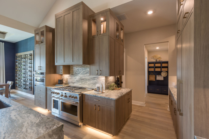 Kitchen in Reveur warm woodgrain with custom vent hood and Slim Shaker doors
