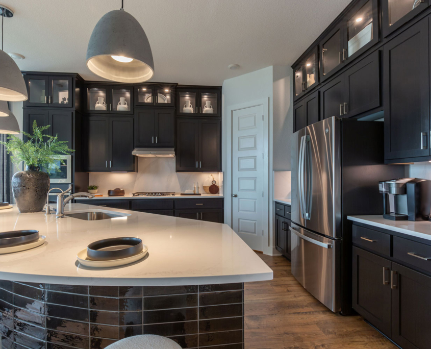 Black kitchen cabinets in Breu with glass uppers and black tile island back