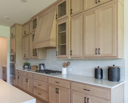 Kitchen cabinets in Maple Savaii with Shaker doors and Shaker range hood, tall uppers and glass cabinet doors