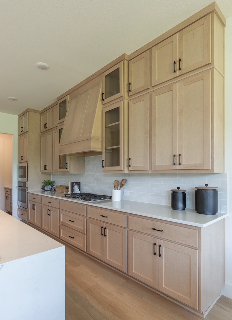 Kitchen cabinets in Maple Savaii with Shaker doors and Shaker range hood, tall uppers and glass cabinet doors