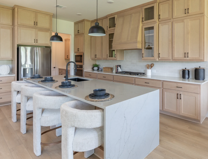 Kitchen in maple Savaii with Shaker doors with black pull handles and custom Shaker wood range hood, refrigerator shroud and waterfall island