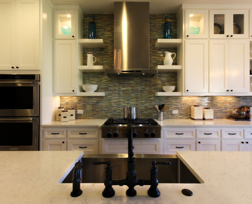Burrows Cabinets' white kitchen with Terrazzo doors, floating shelves, glass inserts in upper doors
