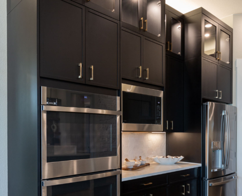 Kitchen oven wall cabinets in Breu muted black paint with Slim Shaker doors and gold pulls