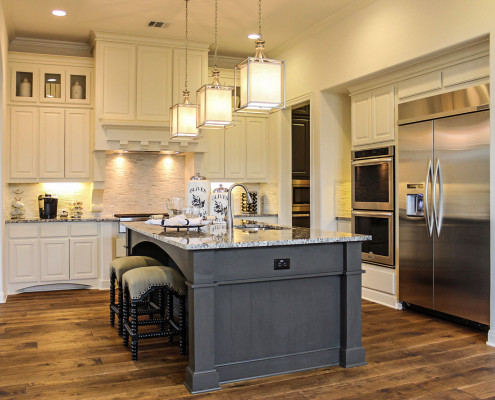 Burrows Cabinets' kitchen cabinets in bone white with custom wood vent hood and Umber gray island