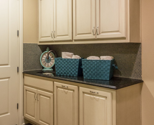 Burrows Cabinets' laundry room cabinets in bone with brown glaze