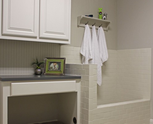 Burrows Cabinets' laundry room cabinets painted white with built-in dog shower