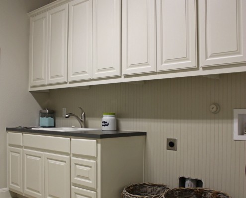 Burrows Cabinets' laundry room cabinets painted white with built-in sink