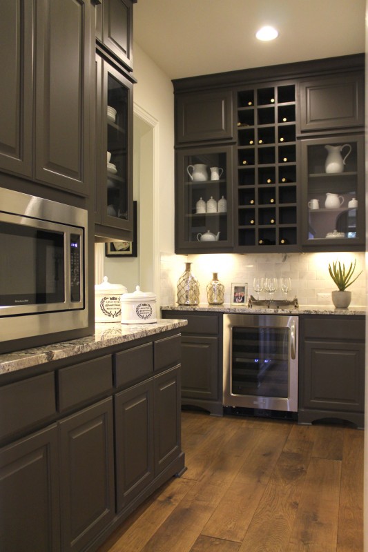 Burrows Cabinets' pantry cabinets with wine storage and glass doors in Umber gray