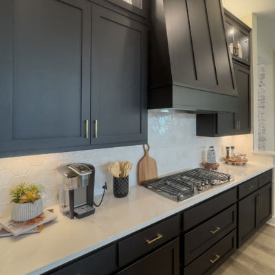 Kitchen cabinets with Breu black paint and gold hardware with Shaker vent hood